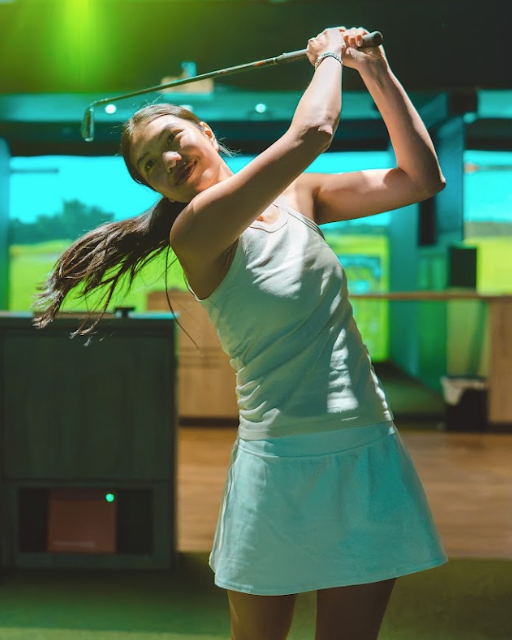 Sam mid-swing in a GolfSpace simulator bay.